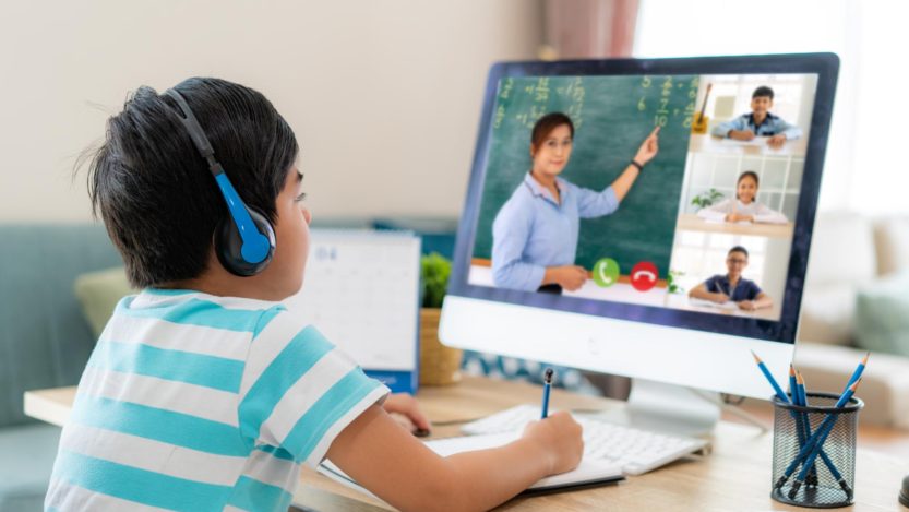 Clases virtuales, niño frente a computadora con audífonos en clase.