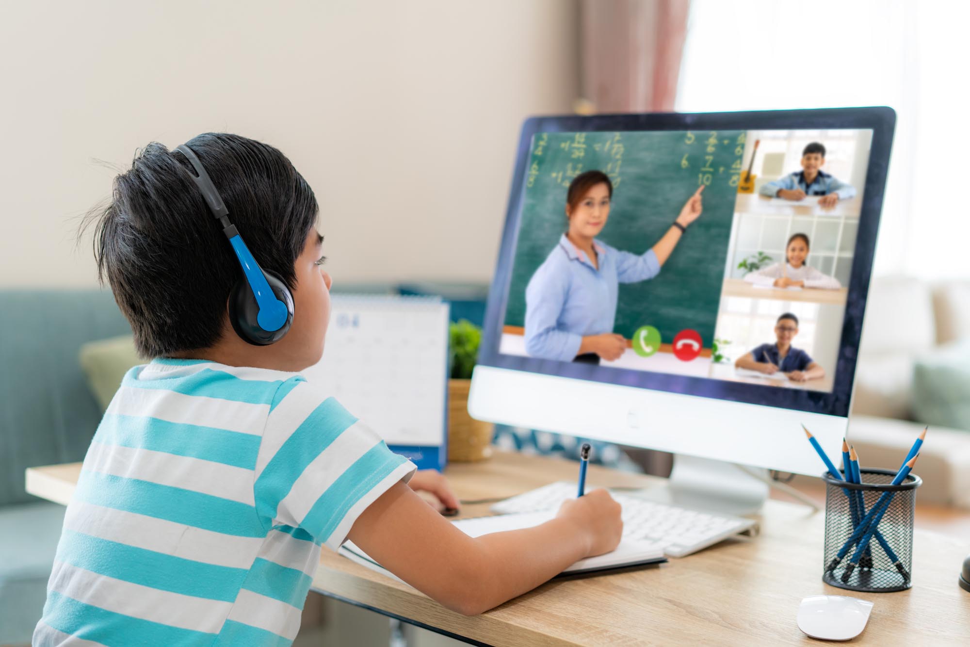 Clases virtuales, niño frente a computadora con audífonos en clase.